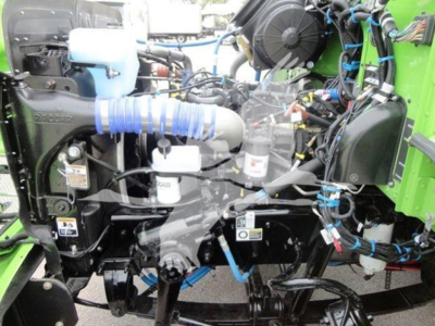 Peterbilt 337 engine bay showing coolant reservoir, hoses, wiring, and engine components in green truck bed.