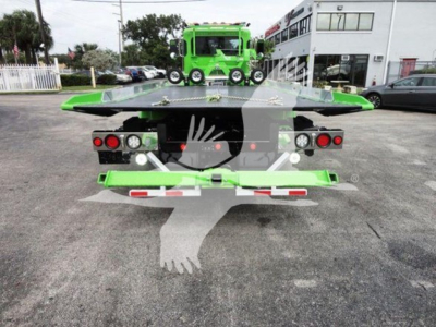 Back view of a green Peterbilt 337 rollback tow truck showing loading bed with red tail lights and rear bumper.