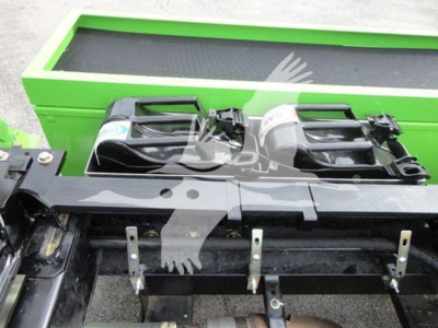 Peterbilt 337 rollback truck front display showing twin batteries and metal mounts, with a bright green equipment trailer in the background.