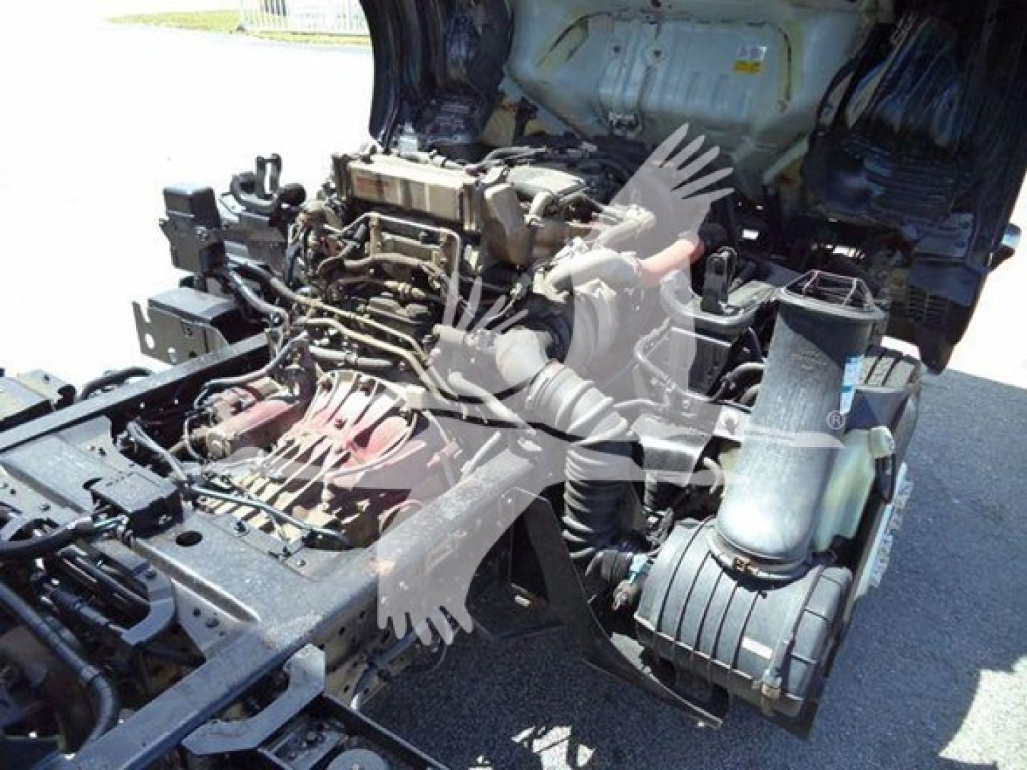 Isuzu NRR truck engine bay with exposed diesel engine and turbo, showing intake manifold, wiring, and surrounding components.
