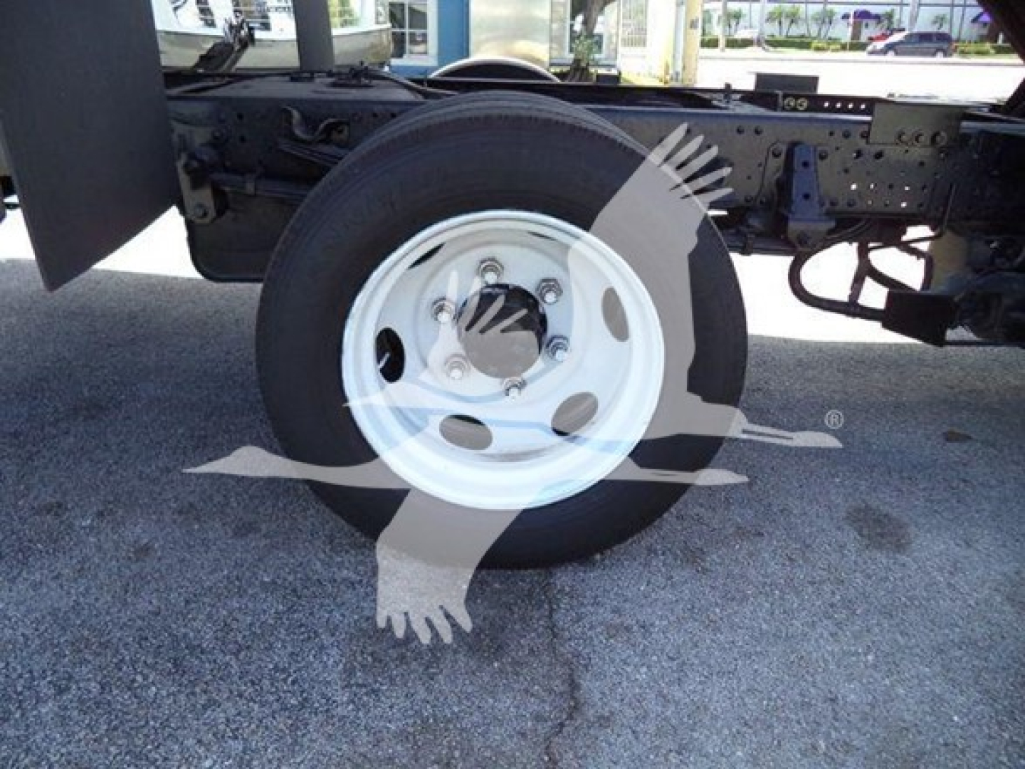 Isuzu NRR truck chassis with front wheel visible and white steel rim; no legible labels visible on components.