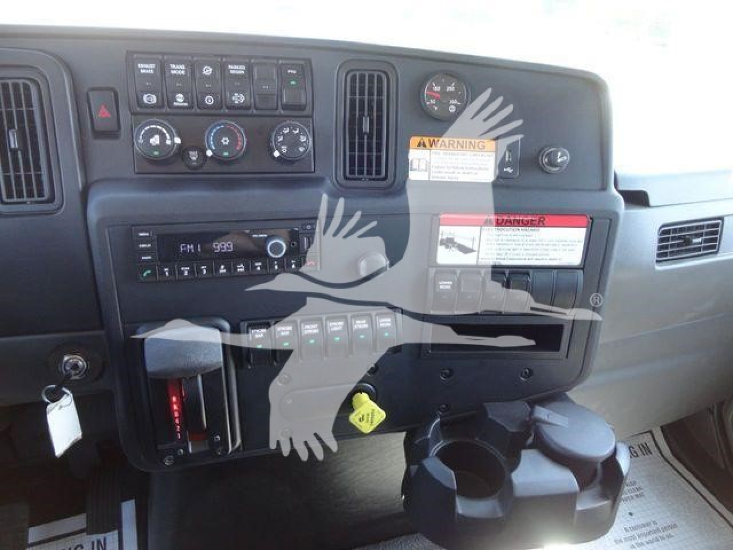 Dashboard view of a 2022 International MV rollback truck showing instrument cluster, controls, warning stickers, and cup holder.