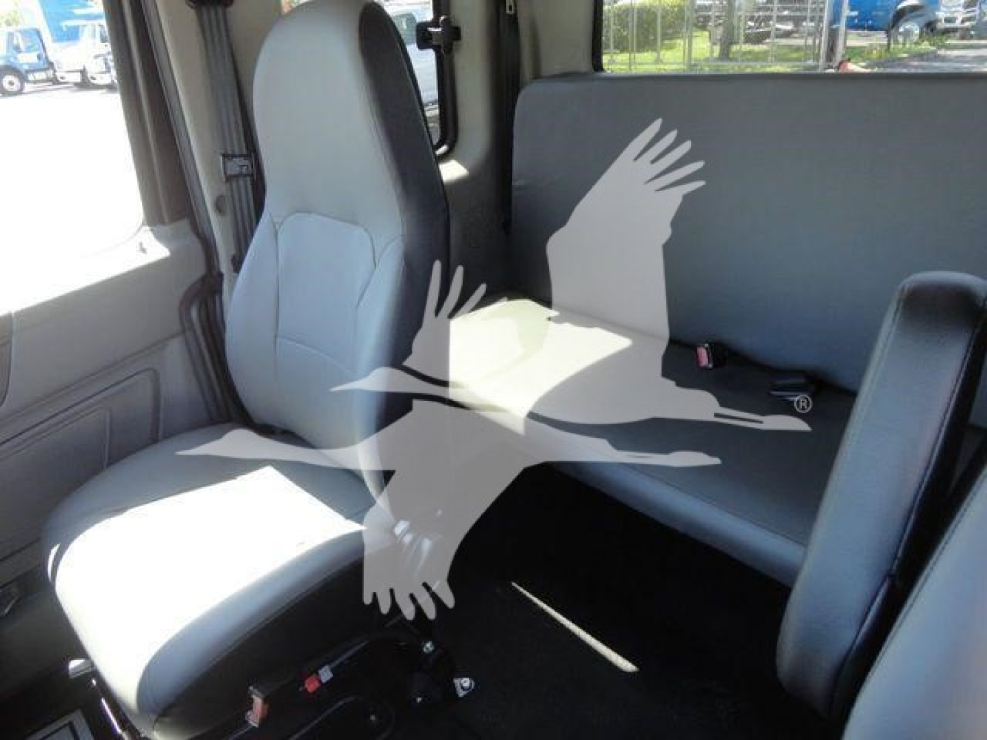 Interior of a 2022 International MV cab showing front seat and a rear bench seat with light gray upholstery.
