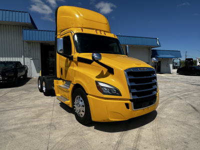 Yellow Freightliner Cascadia 126 daycab tractor in a lot, front three-quarter view, black grille, large mirrors, VIN sticker not visible.
