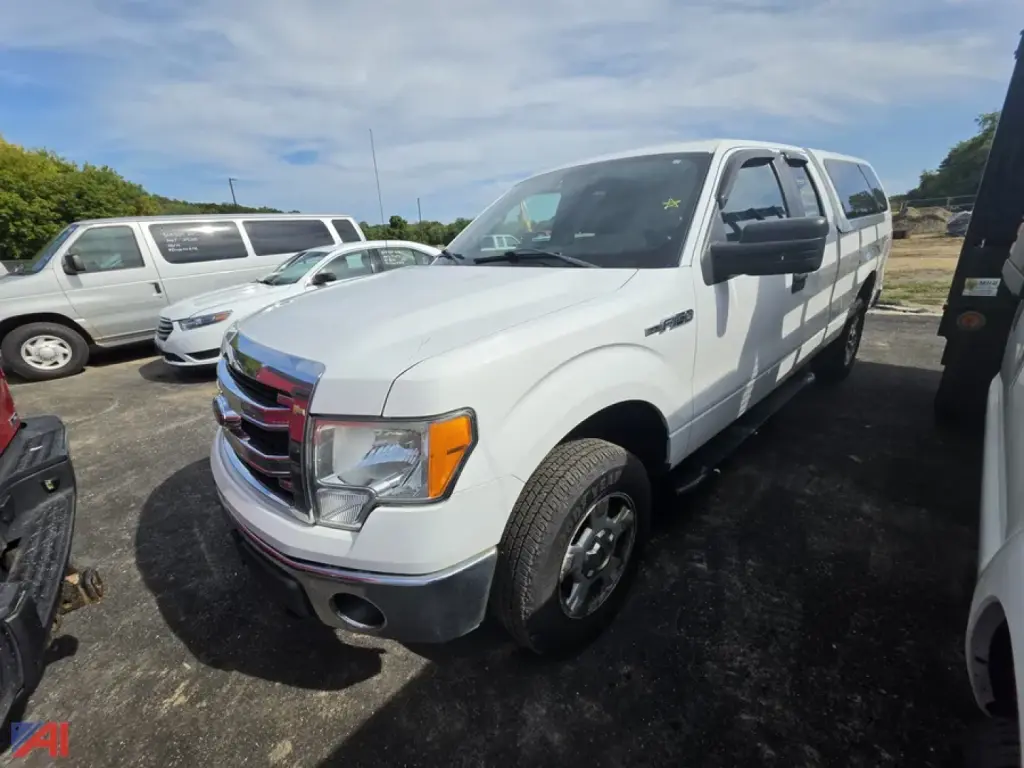 Ford F-150 pickup truck 2014 white 4x4 showing front-left angle with extended cargo van in background.