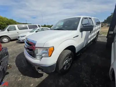 Ford F-150 pickup truck 2014 white 4x4 showing front-left angle with extended cargo van in background.