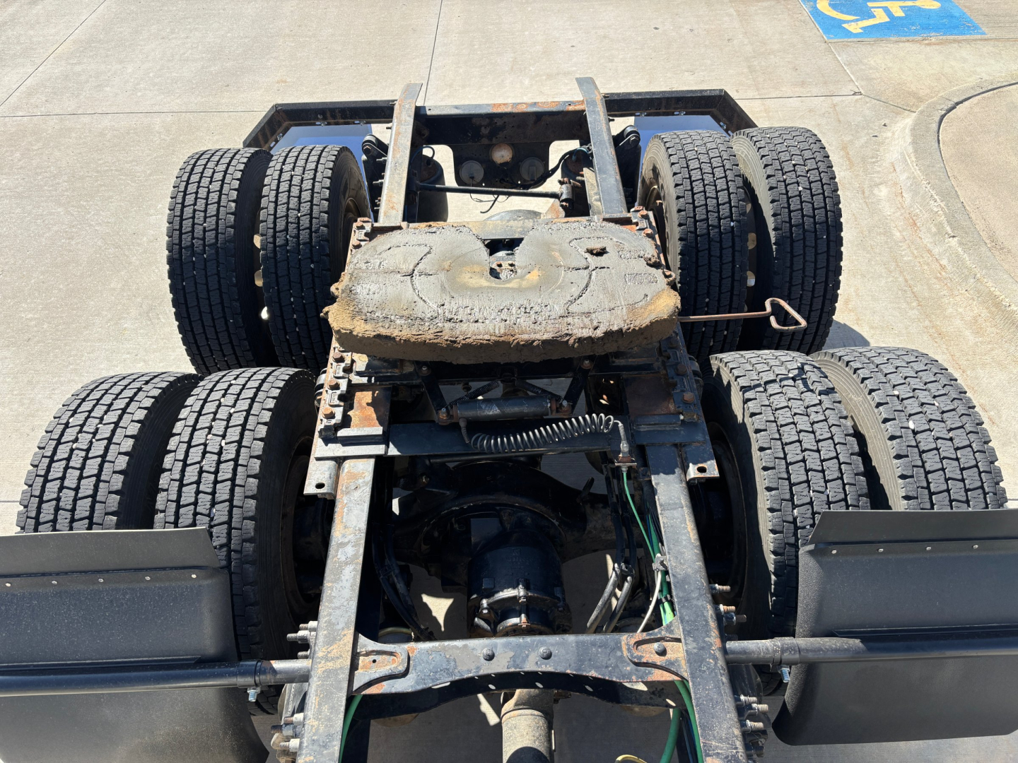 Truck chassis showing fifth wheel area and dual rear axles on a Freightliner CA12564DC chassis with tires and suspension visible.