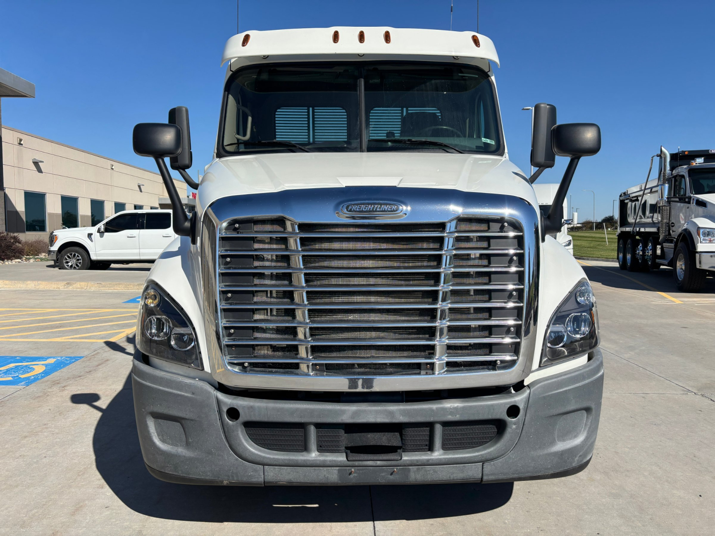 Front view of Freightliner CA12564DC truck showing large chrome grille, headlights, and bumper with mirrors on each side.