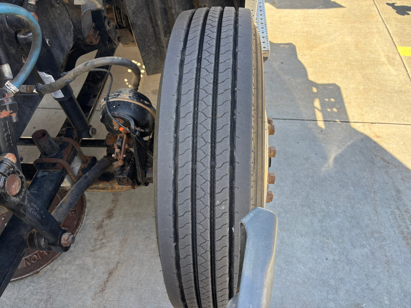 Truck wheel/tire assembly and front suspension of a 2017 Freightliner CA12564DC conventional daycab; visible components include dual front axle with steering linkage and tire tread.