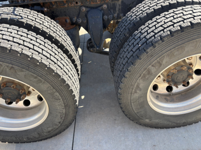 Freightliner CA12564DC truck showing dual rear wheels and suspension components.