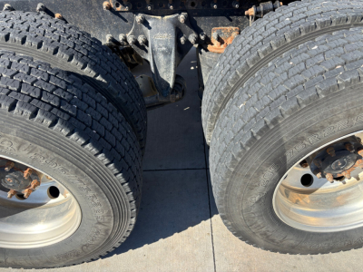Two rear axles and dual tires of a Freightliner CA12564DC truck chassis showing dual wheel rims and suspension components.