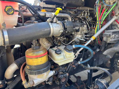 Conventional Daycab truck engine bay with coolant reservoir, hydraulic lines, and various hoses visible.
