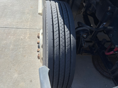 Truck front wheel and suspension view showing dual-tire arrangement and axle components on a Freightliner CA12564DC cab chassis.