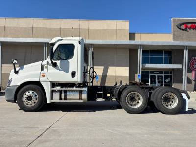 White Freightliner CA12564DC daycab tractor side view showing cab, fuel tanks, and dual rear axles with 6 wheels.
