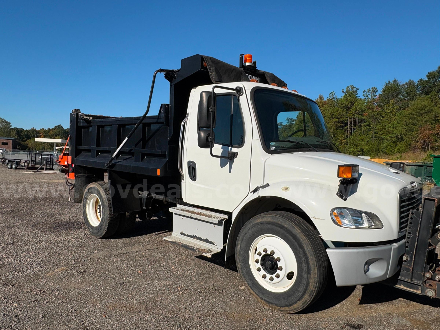 Dump truck in-service 2015 Freightliner M2 with white cab and black dump bed, front-right view.