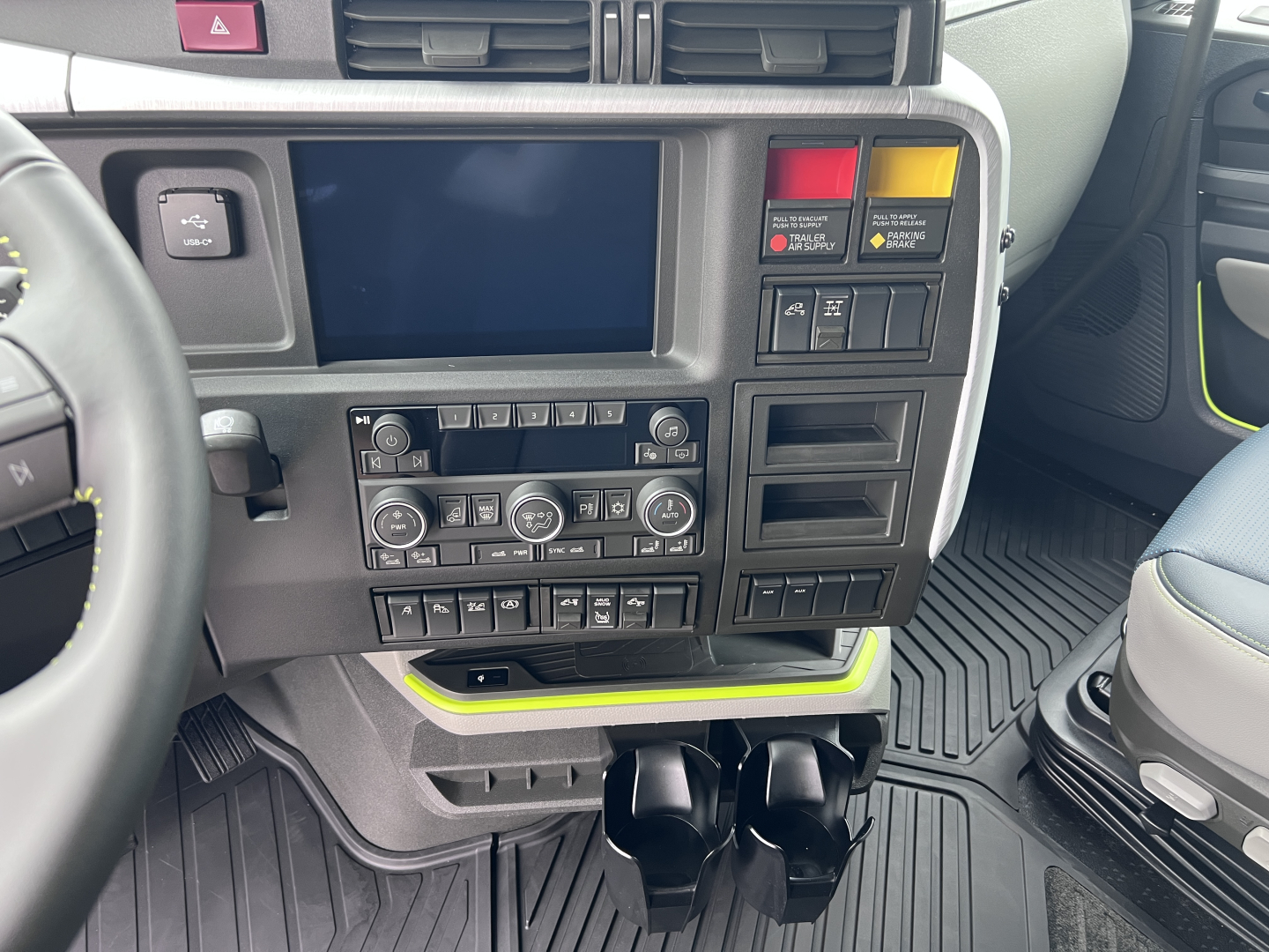 Volvo VNL64T860 cockpit with center touchscreen, climate controls, and cup holders.