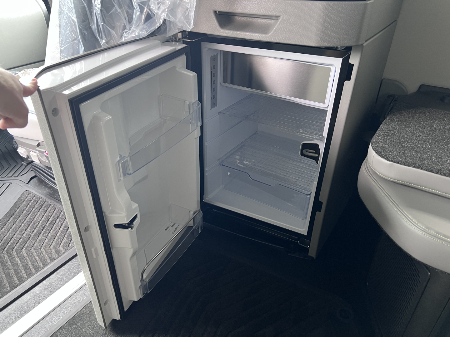 Volvo VNL64T860 cab interior showing open mini fridge with doors and empty small freezer compartment in the sleeper cab.