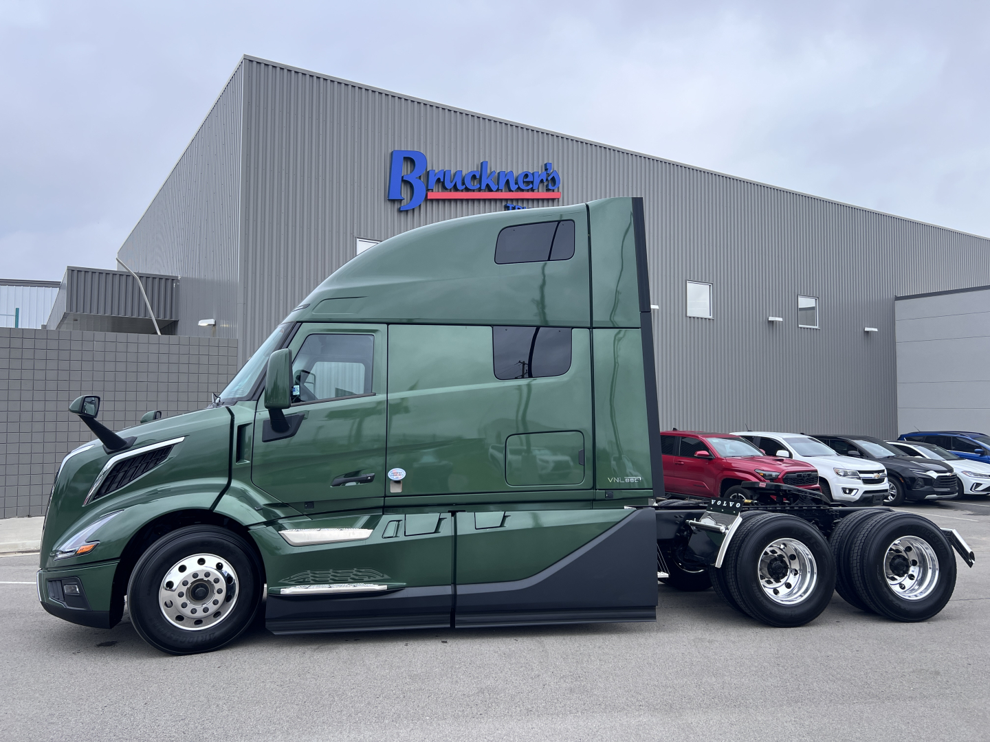 Volvo VNL64T860 in-service sleeper cab tractor showing 6x4 rear with triple rear axles and green exterior.