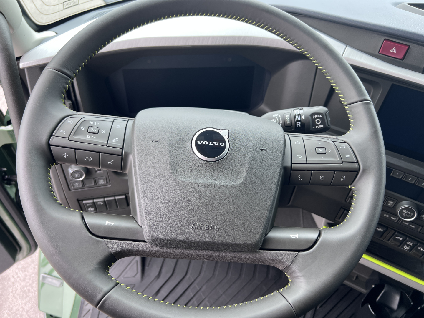 Steering wheel of a Volvo truck showing Volvo emblem and control stalks, interior view