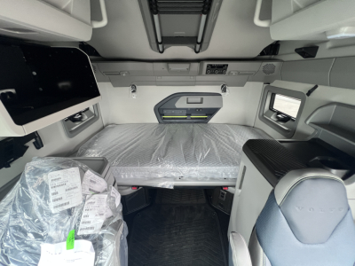 Volvo VNL interior sleeper cab showing bed with plastic wrap and overhead storage panels.