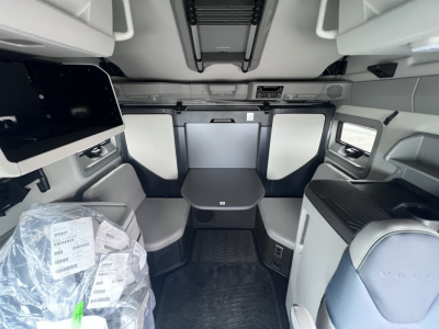 Volvo VNL sleeper cab interior showing seating area with table, cabinets, and overhead storage.