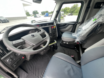 Volvo VNL64T860 truck cab interior showing steering wheel, dashboard, and driver seat with plastic-covered passenger seat.