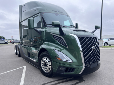 Volvo VNL64T860 truck in green with sleeper cab showing front grille, headlights, and side mirrors.