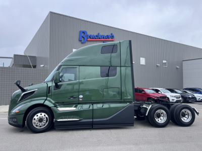 Volvo VNL64T860 in-service sleeper cab tractor showing 6x4 rear with triple rear axles and green exterior.