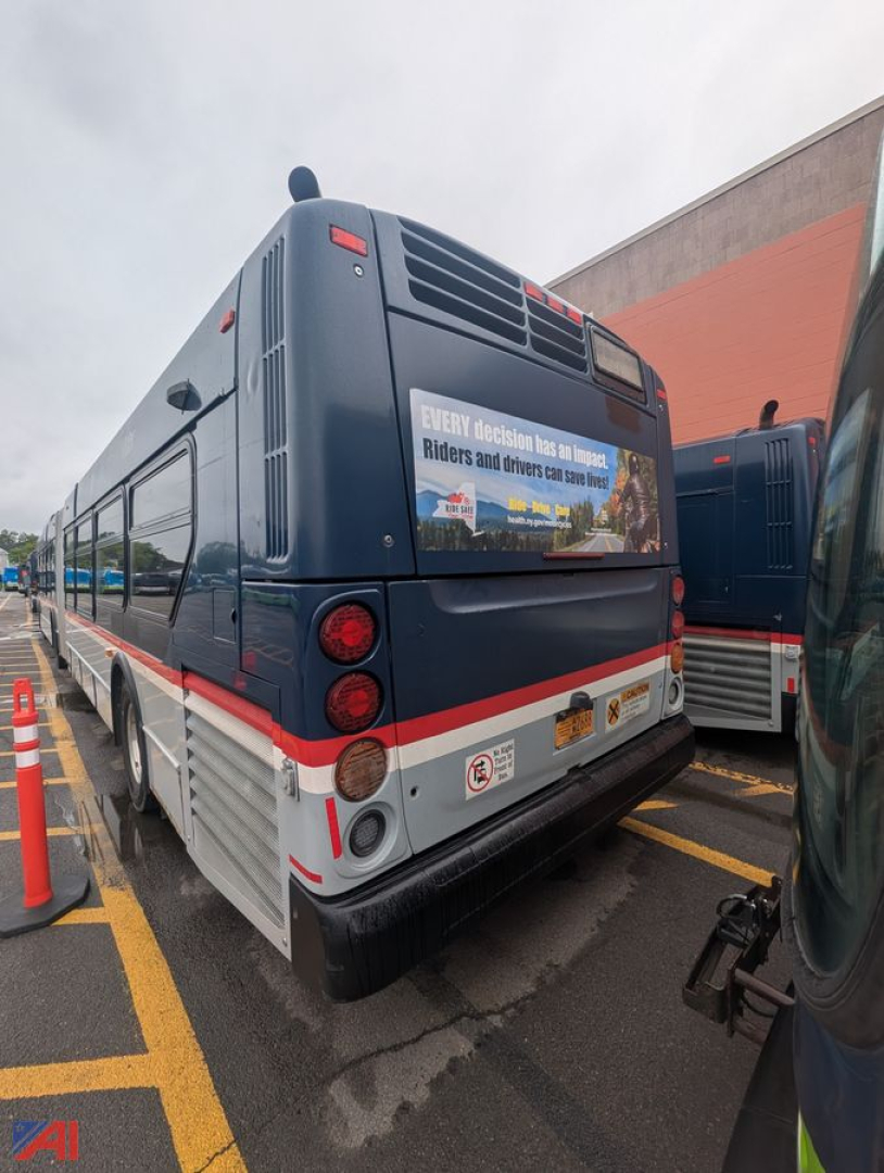 Bus rear view of 2013 New Flyer XD60 transit bus in a parking lot showing rear lights, bumper, and a vinyl advertisement on the back.