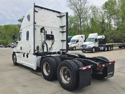 Freightliner Cascadia125/126 truck cab and rear chassis view, white sleeper tractor, dual rear axles, fifth-wheel area visible, other trucks in background.