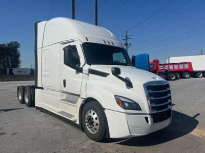 Truck cab front-left view showing Freightliner Cascadia 126 with white exterior, sleeper, large grille, side mirrors, and stacked dual rear wheels.