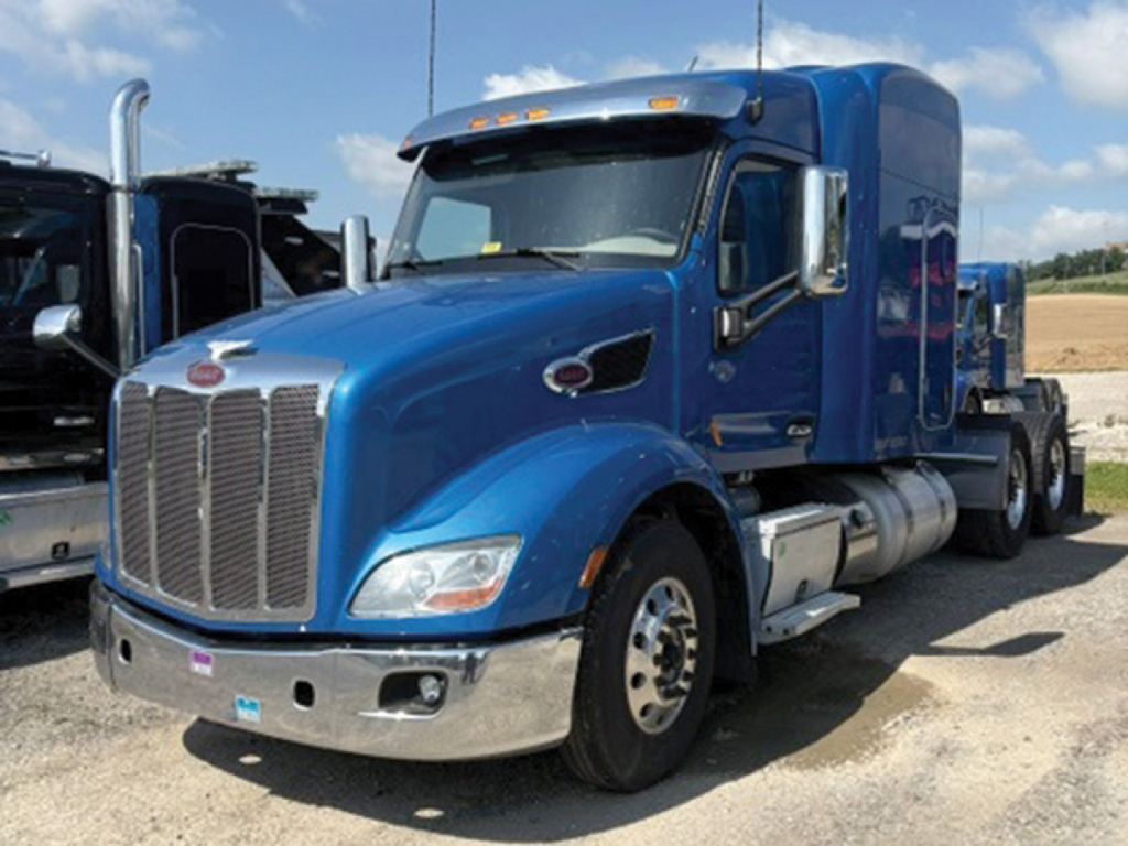 Peterbilt 579 UltraCab conventional sleeper truck blue exterior side view showing front grille chrome bumper and dual fuel tanks.