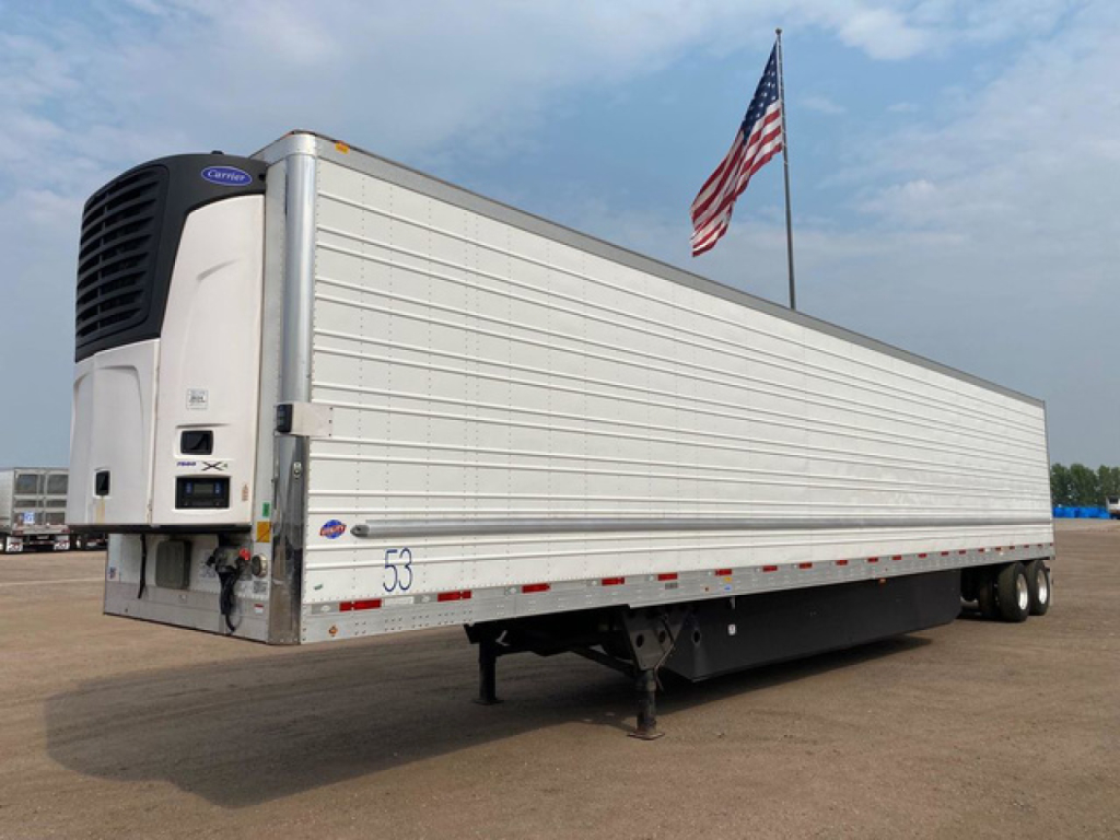 Utility reefer trailer with refrigerated body and attached front refrigeration unit, side view showing metal paneled walls and landing gear.
