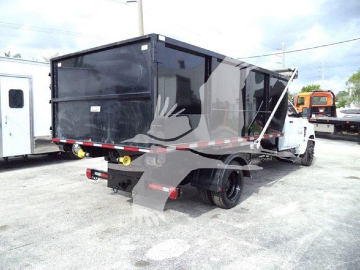 Truck bed or roll-off dump truck rear view showing cargo container with hydraulic components and tires.