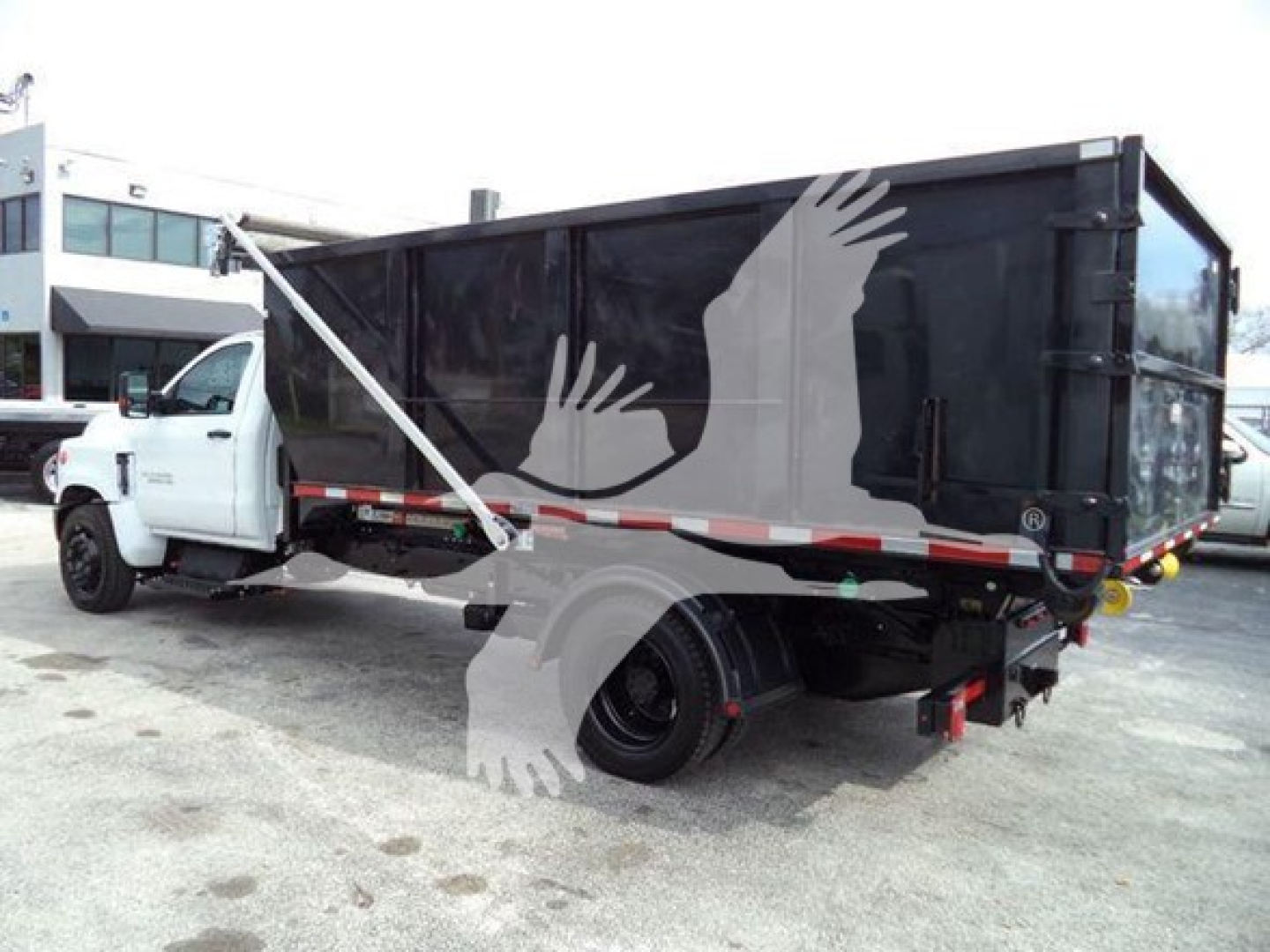 Truck bed of a 2023 Chevrolet Silverado 6500HD roll-off truck showing side of cargo box and rear wheels.