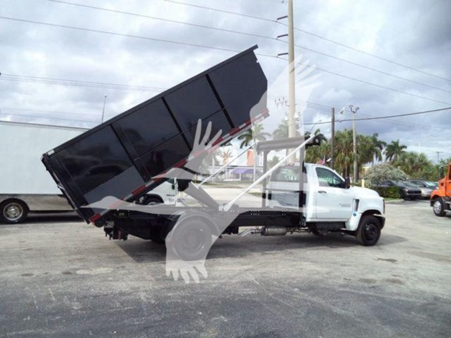Truck with dump bed raised in a Chevrolet Silverado 6500HD roll-off configuration showing hydraulic lift and dump bed.
