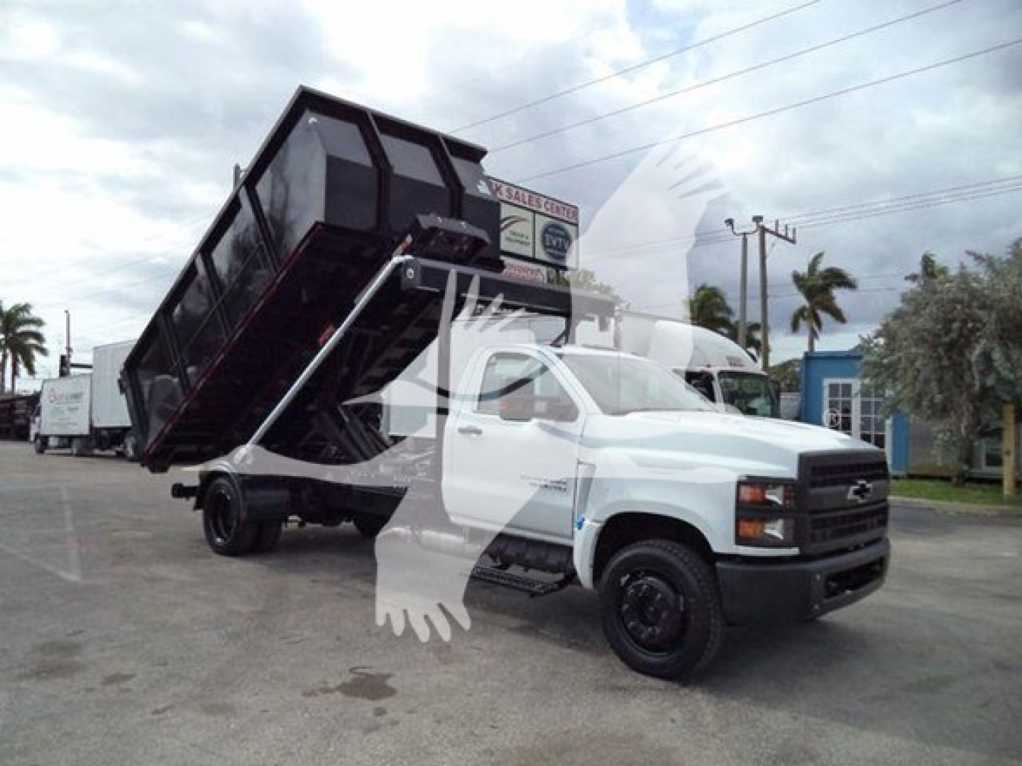 Truck with a raised dump bed on a Chevrolet Silverado 6500HD chassis in a dealership lot.
