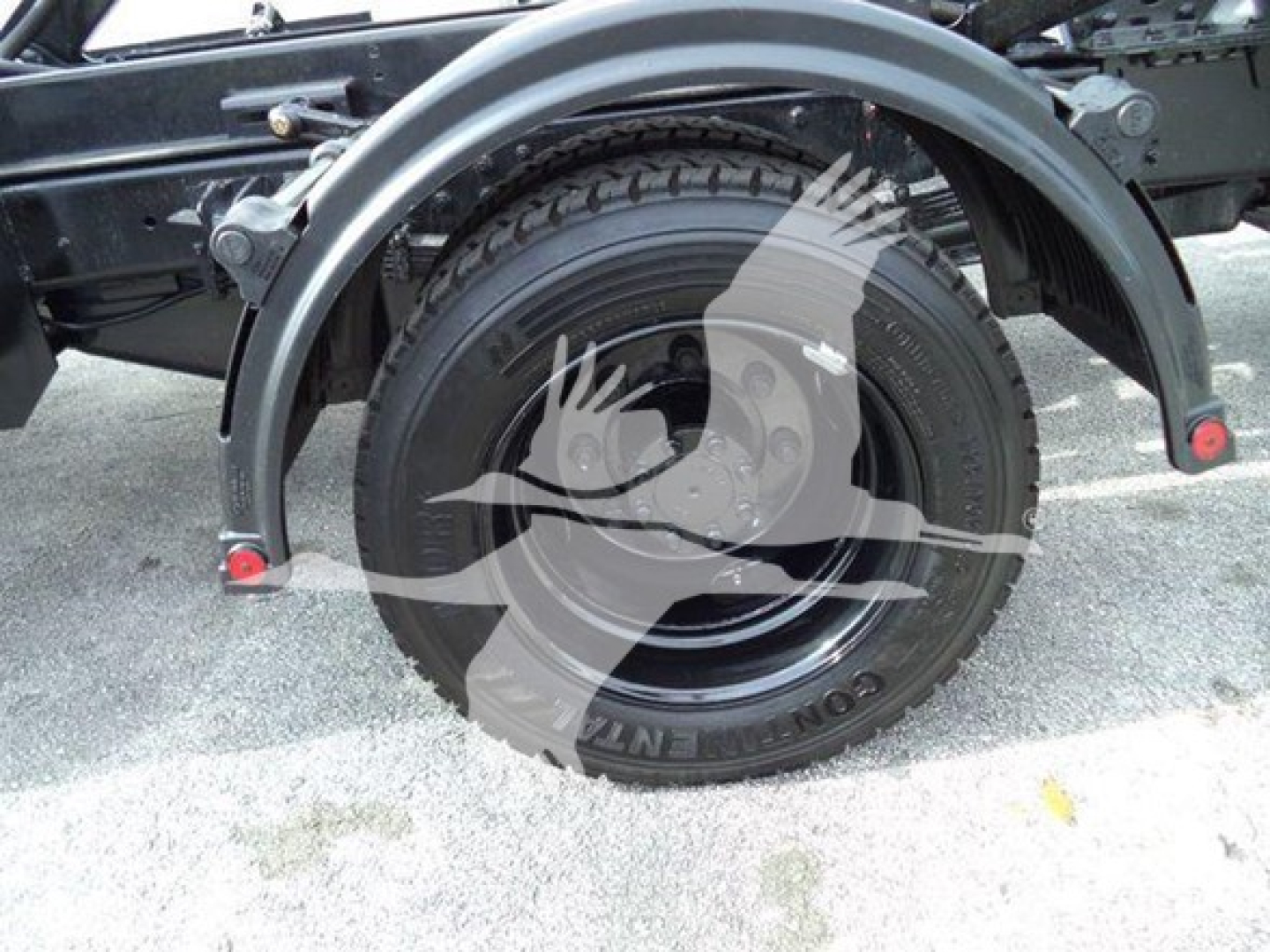Truck rear wheel and fender view showing spare wheel well and tire treads.