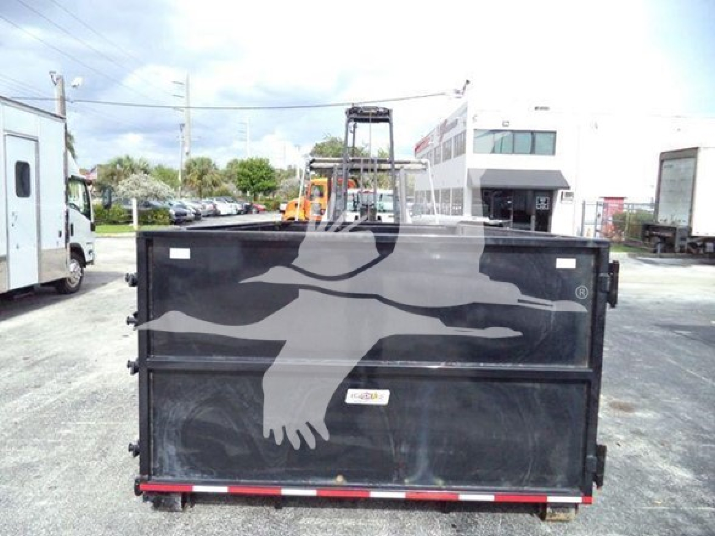 Rear view of a black dump/roll-off truck bed on a Silverado 6500HD chassis with a red-and-white reflective strip along the bottom edge.
