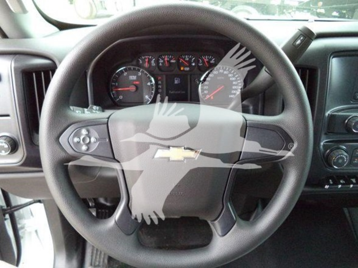Steering wheel and dashboard of a 2023 Chevrolet Silverado 6500HD under view with instrument cluster and Chevrolet emblem on the steering wheel.