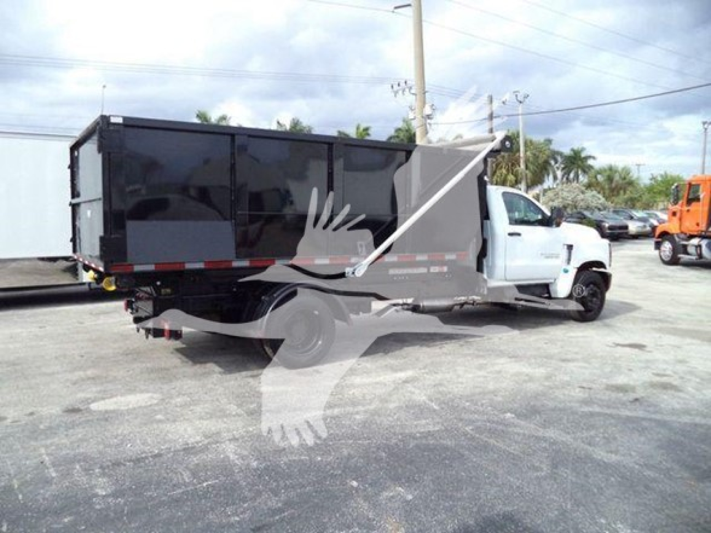 Truck chassis showing a large black dump body on a white Chevrolet Silverado 6500HD cab; no legible labels visible on body.