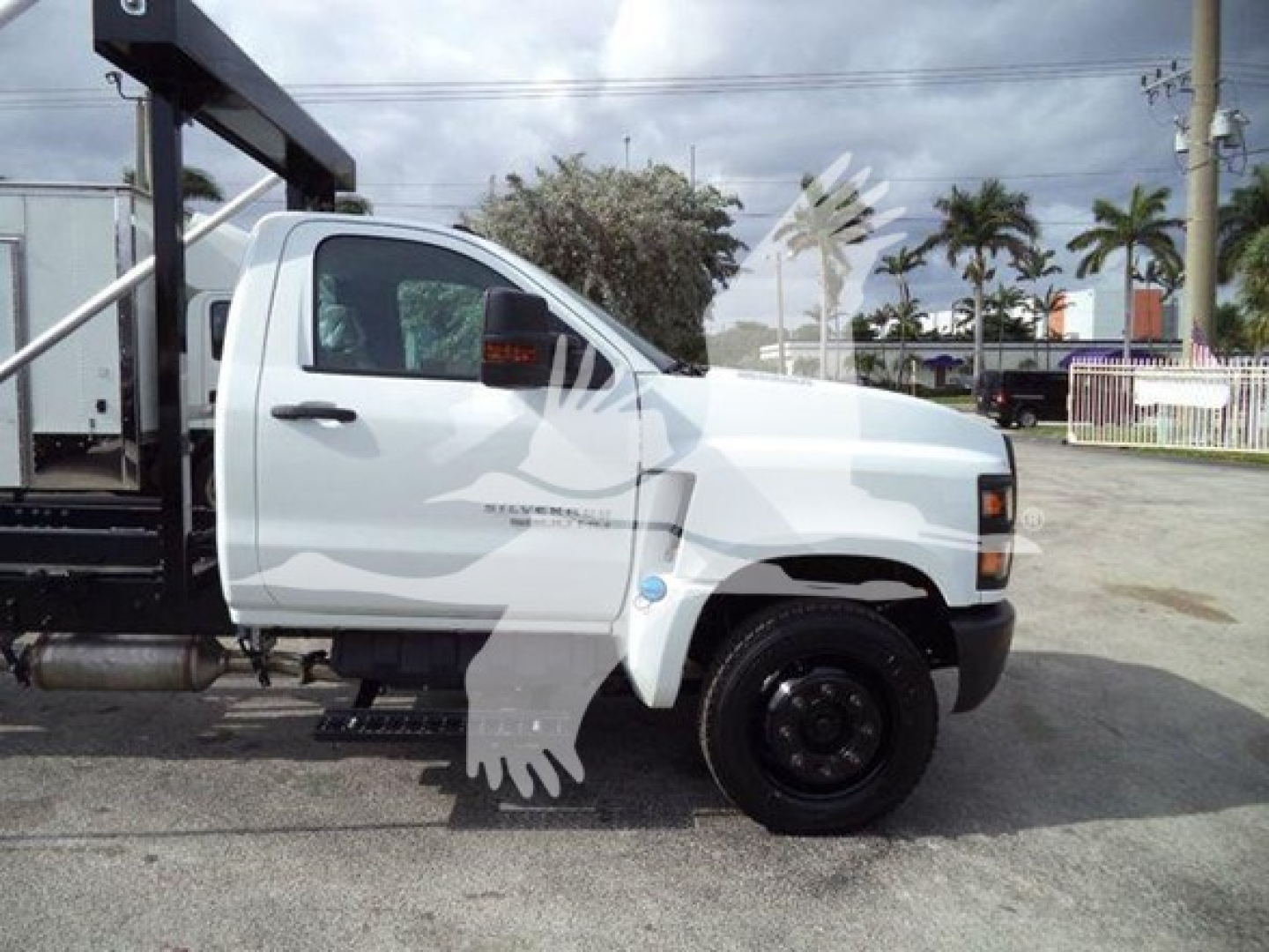 Truck side view of a 2023 Chevrolet Silverado 6500HD sleeper cab with a roll-off bed, white exterior, single rear axle, black wheels, and compact cab.