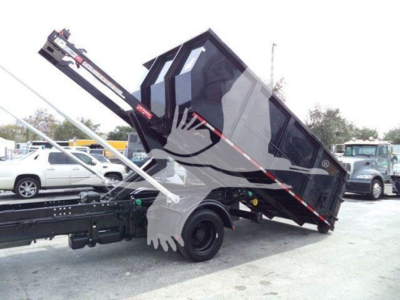 Construction-style dump bed on a Silverado 6500HD chassis in tilted dump position with hydraulic ram visible.