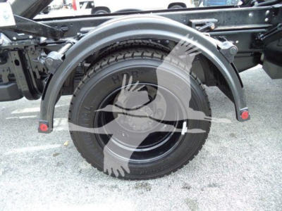 Wheel area of a Chevy Silverado 6500HD rolloff truck showing rear fender, tire, and suspension components with a large wheel and mudguard.