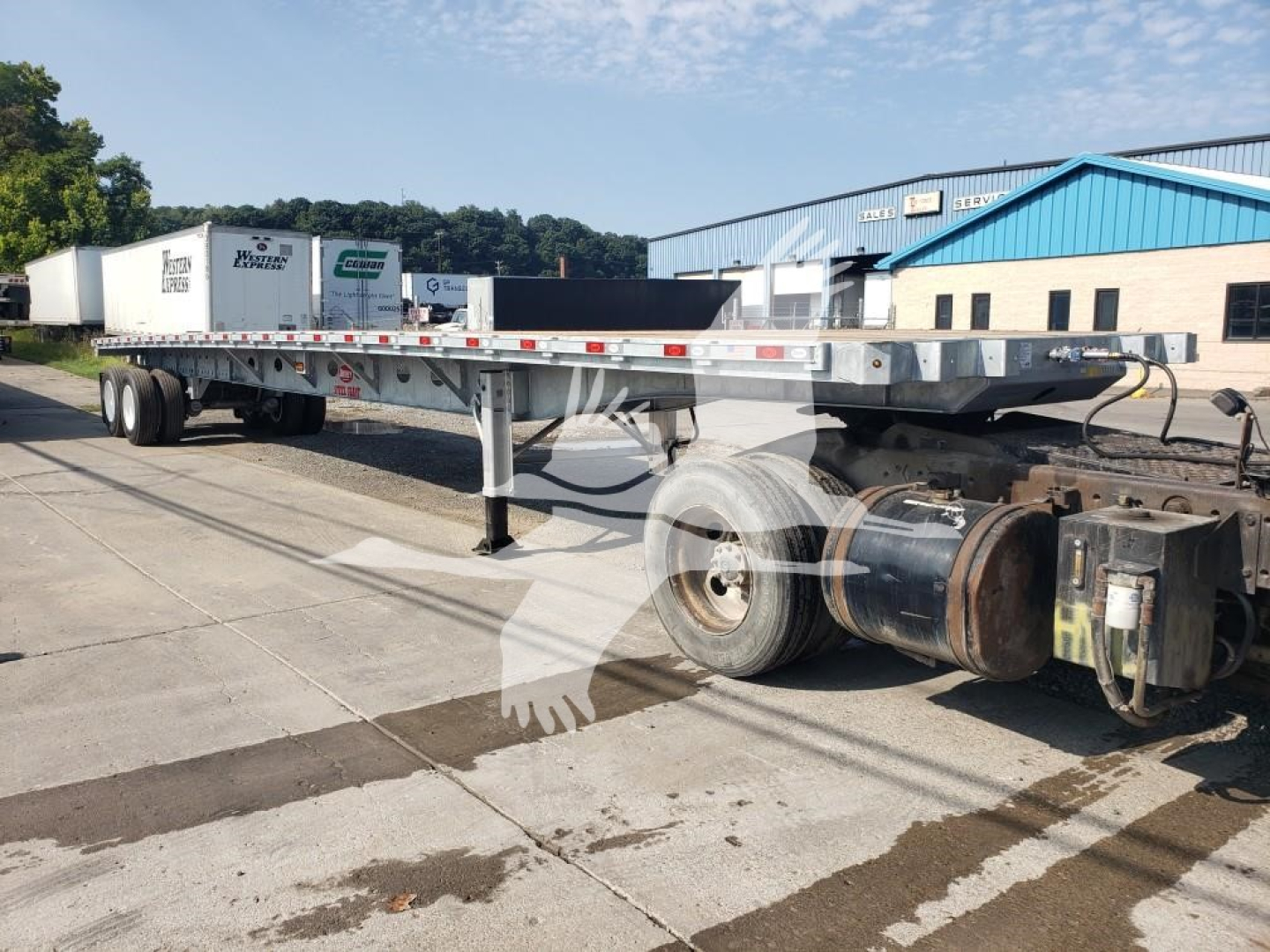 Flatbed trailer with long aluminum deck and dual rear axles showing hitch and cabling; VIN and stock number not visible on trailer.