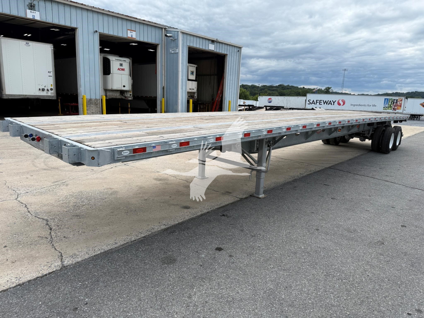 Trailer chassis with a long galvanized flatbed showing underside support and wheels in distance.