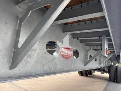 Flatbed trailer underside with galvanized steel frame, side crossmembers, and wheel area visible; Dorsey logo sticker affixed.