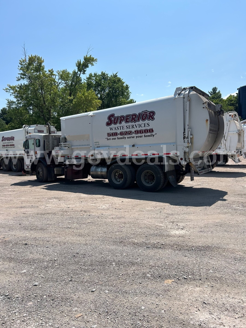 Truck mounted waste services rear view showing Superior Waste Services logo on a white garbage trailer