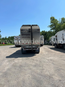Rear view of a 2019 Peterbilt 350 box truck in a lot, showing waste service logo and rear equipment.