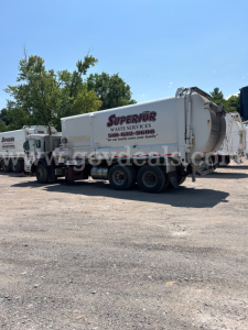 Truck mounted waste services rear view showing Superior Waste Services logo on a white garbage trailer